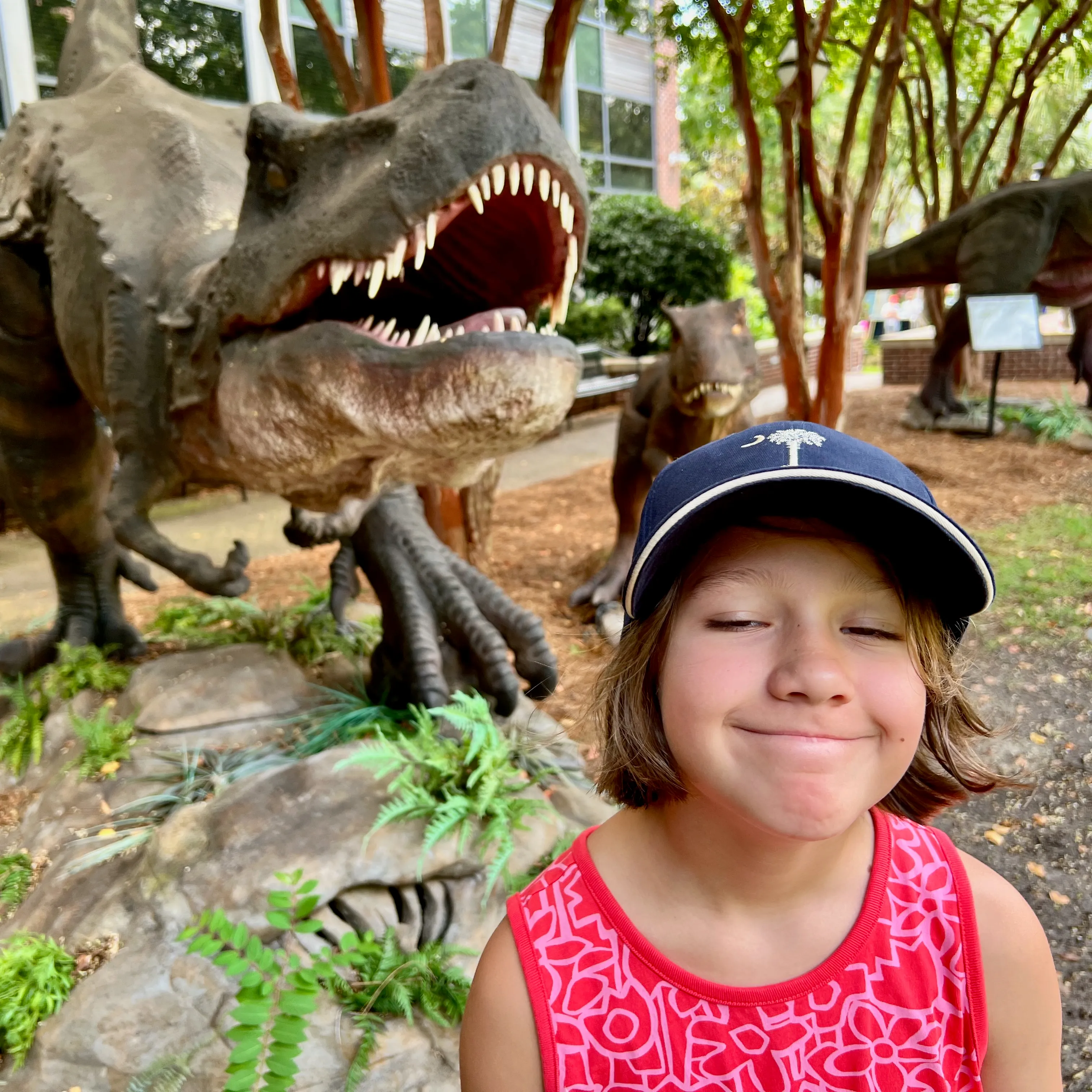 Lorelei making faces in front of a dinosaur.